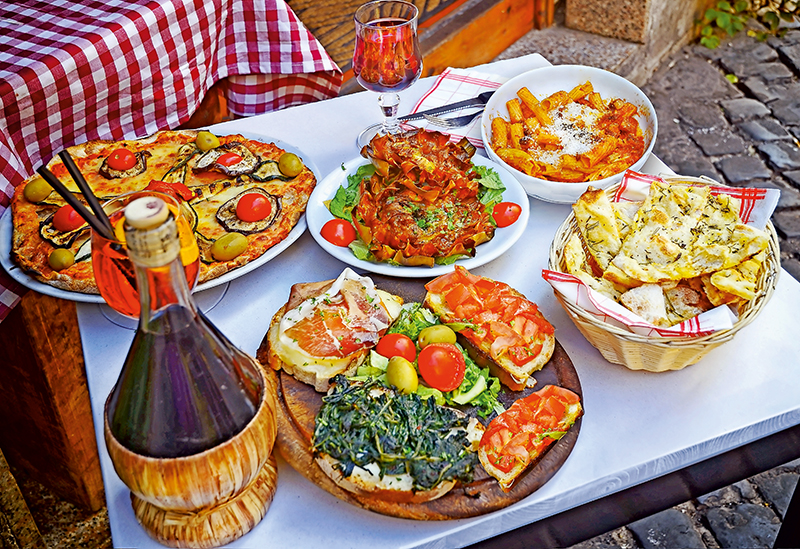 A summer  dinner .Pasta , pizza  and homemade food arrangement  in a restaurant  Rome   .Tasty and authentic Italian food.