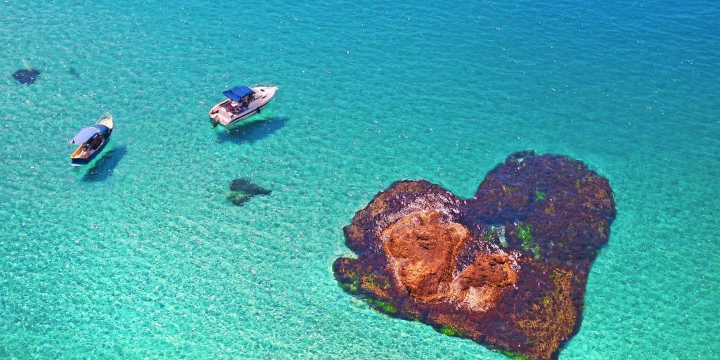 boats floating near the stone in the shape of heart. Romantic island lovers